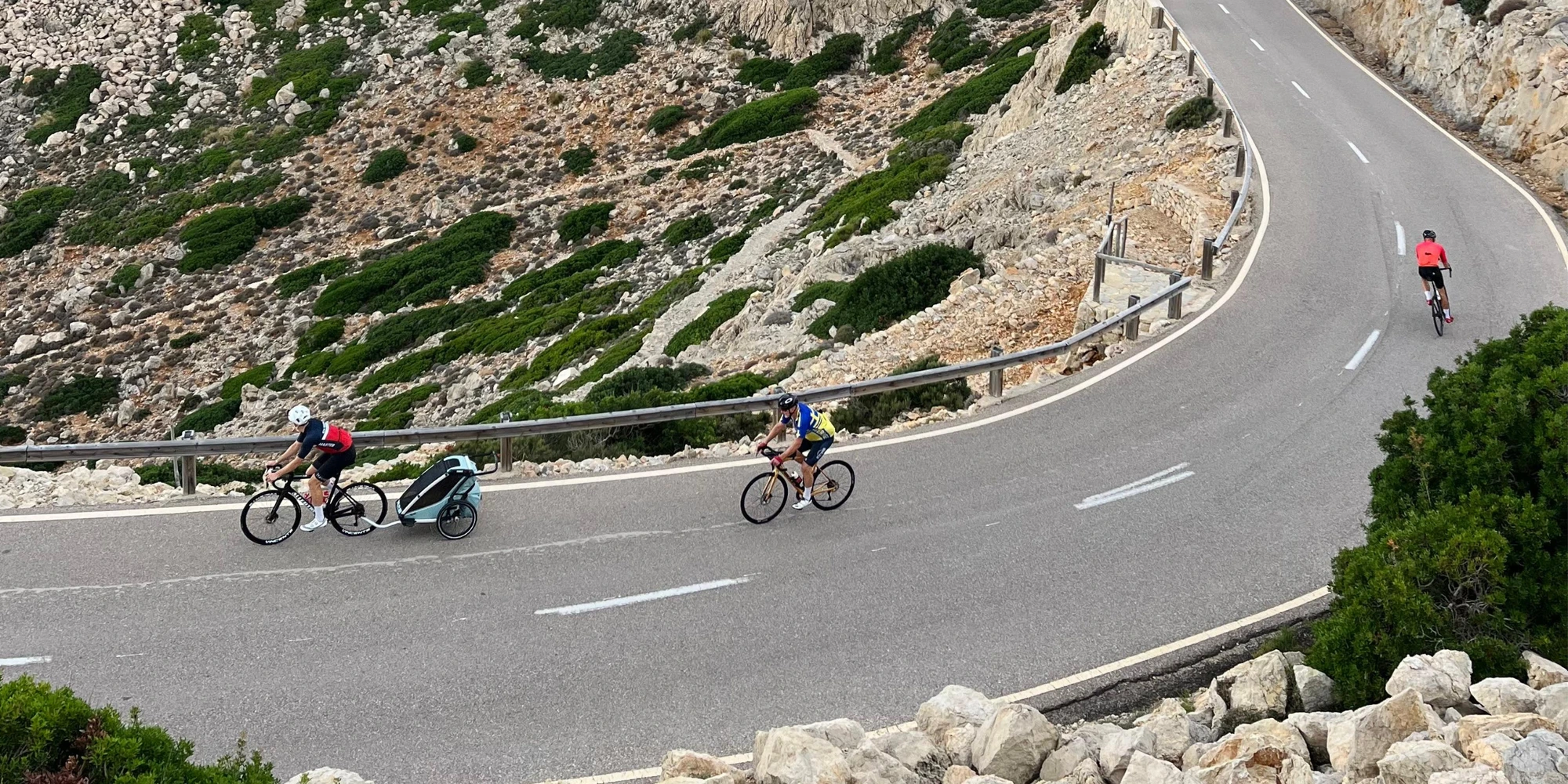 En cyklist på en slingrande bergsväg drar en cykelvagn.