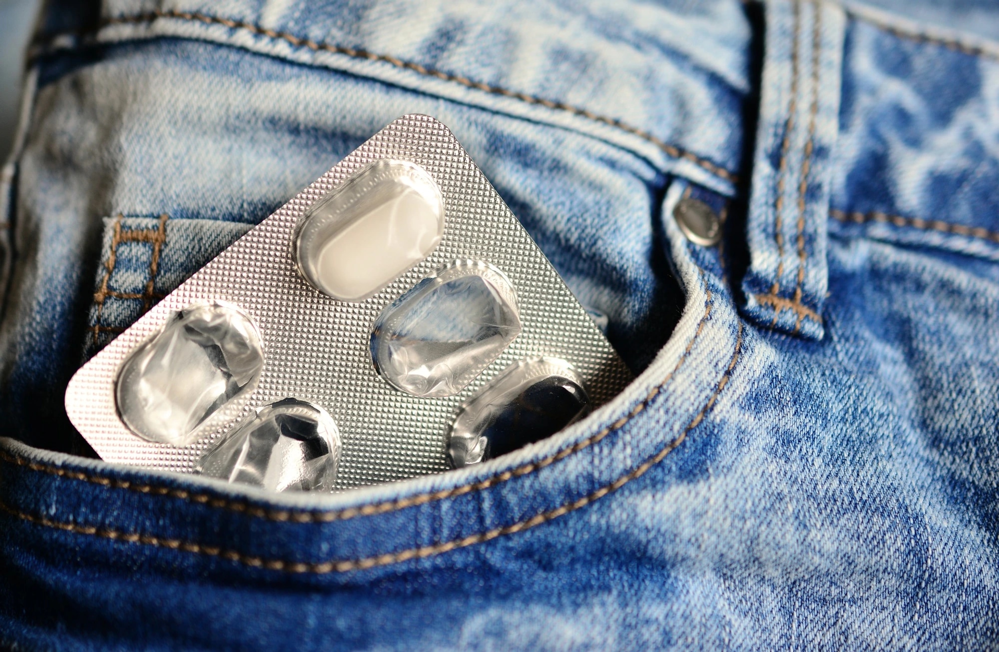 Blisterpackung mit schmerzlindernden Tabletten in der Jeans-Tasche.