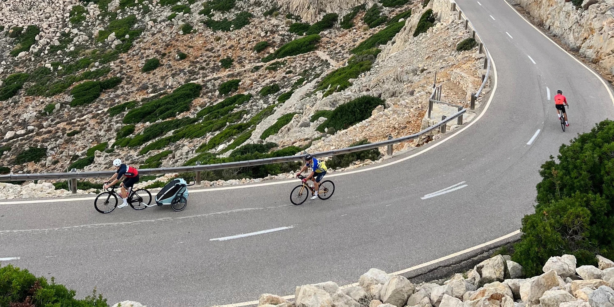 En cyklist på en slingrande bergsväg drar en cykelvagn.
